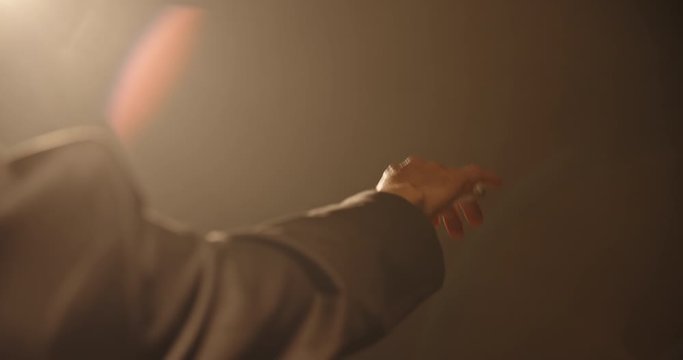 Close up shot of hand of unrecognizable orchesra conductor waving his stick and directing musicians during a rehearsal. Studio shot on black background 4k footage
