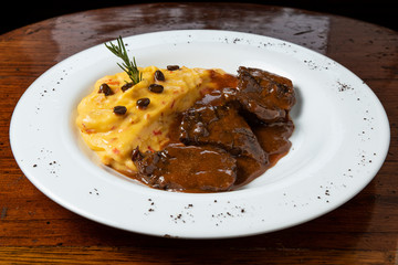 Delicious braised beef roast with creamy mashed potatoes. Loin with coffee and mashed potatoes. Wooden background.