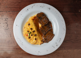 Delicious braised beef roast with creamy mashed potatoes. Loin with coffee and mashed potatoes. Wooden background. Top view.