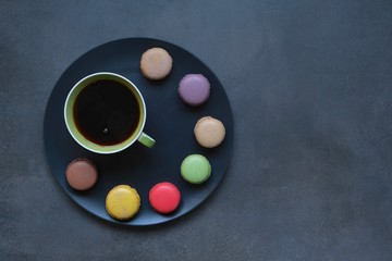 Obraz na płótnie Canvas Cup of coffee and colored macaroons on a dark background. Coffee mood.