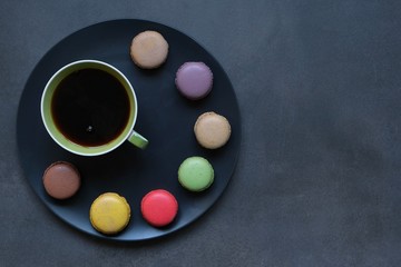 Obraz na płótnie Canvas Cup of coffee and colored macaroons on a dark background. Coffee mood 