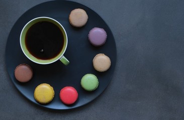cup of coffee and sweets colored macaroons on a dark background. Coffee mood 