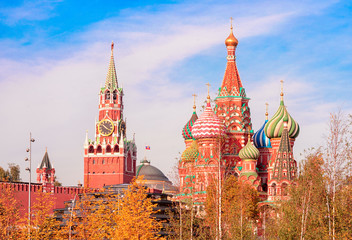 View of the Spasskaya Tower, the Moscow Kremlin and St. Basil's Cathedral from autumnal Zaryadie park. Architecture and sights of Moscow. - obrazy, fototapety, plakaty