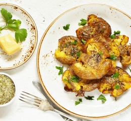 crushed potatoes. smashed potatoes. recipes for Australian cuisine. the potatoes are boiled in a shell, broken and baked in an oven with spices. top view