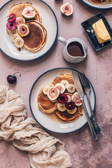 Freshly baked pancakes with fruits, butter and maple syrup