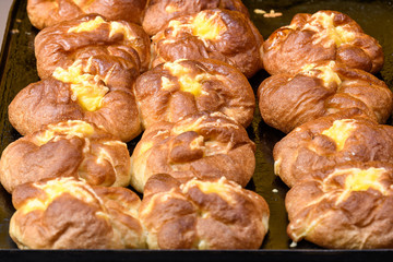 Small vanilla and cheese home made pies in display at a street food market, in soft focus