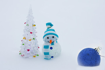 Holiday New year and Christmas. Beautiful winter snowman on white snow and green Christmas tree.