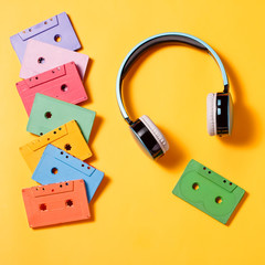 Fototapeta premium Painted audio cassettes on bright multicolor background, copy space, top view. Retro musical background