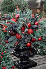 Winter decor. Beautiful arrangement of christmas tree red balls, cones, natural spruce branches for indoor outdoor festive decorating the house for the Christmas New Year holidays.