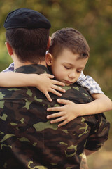 Boy and soldier in a military uniform say goodbye before a separation
