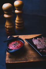 Rolled beef steak with tomato sauce with black background.