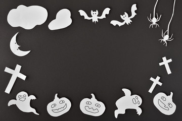 Halloween craft background with white paper cutouts on black cardboard