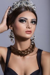 Portrait of beautiful brunette woman in crown with makeup in fashion black clothes