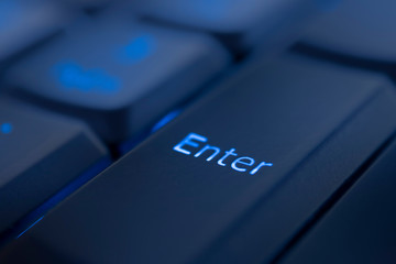 Enter key illuminated by blue LED light. Close-up of computer keyboard.