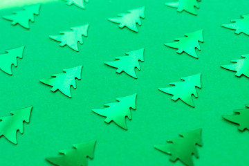 Metallic Christmas trees on a trendy green background. Bright new year's concept. Shiny decorative elements pattern. Selective focus.