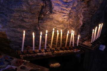 Row of lit candles on offer to the cult of the Virgin Mary (Madonna), in the cave of the sanctuary of the Mentorella, in Guadagnolo. Rome, Lazio, Italy. Sacred place of prayer, peace and silence.