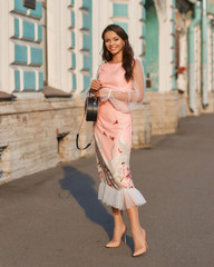 Young pretty woman wearing elegant pink dress on a sunny evening. Beautiful girl with long wavy...