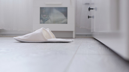 Comfortable White and Fluffy Slippers Waiting in Front of Bed in Bedroom
