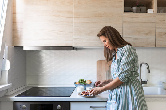 Beautiful Caucasian woman preparing breakfast at kitchen.