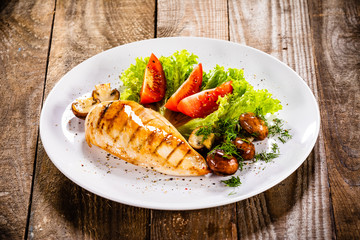 Grilled chicken fillet and vegetables on white plate
