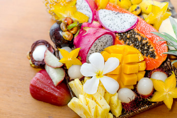Juicy ripe tropical Thai fruits on a wooden dish.