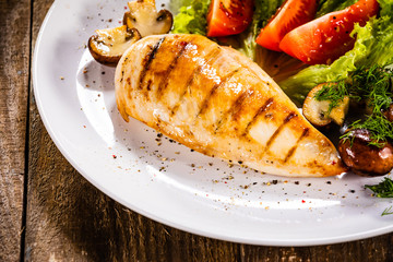 Grilled chicken fillet and vegetables on white plate