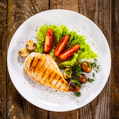 Grilled chicken fillet and vegetables on white plate