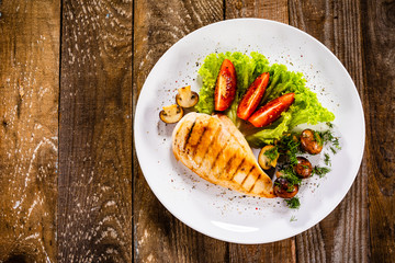 Grilled chicken fillet and vegetables on white plate