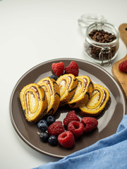 Słodka rolada z kremem i owocami. Pyszne ciasto na deser. Jasne tło.