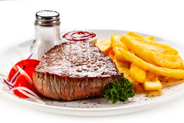 Grilled steaks, French fries and vegetables