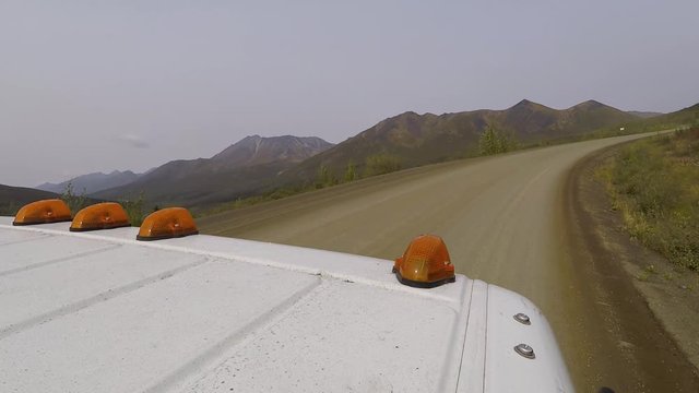 Top pov view of a commercial work truck with orange clearance lights driving off road up a mountain.