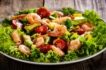 Salad with shrimps on wooden background