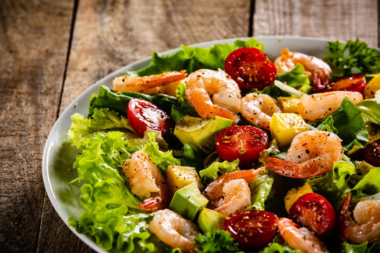 Salad with shrimps on wooden background