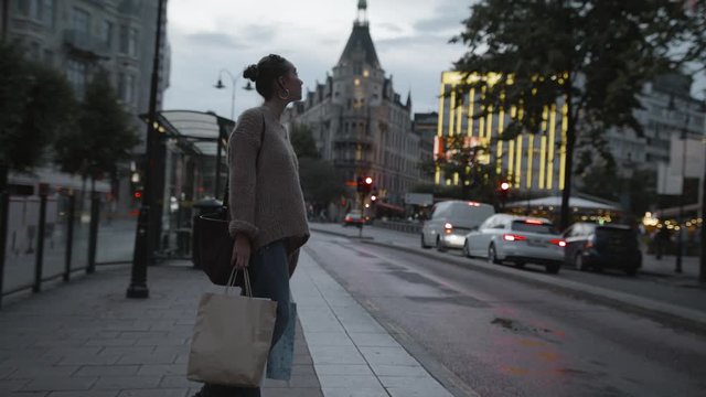 A woman picking up her shopping bags at a bus stop