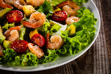 Salad with shrimps on wooden background