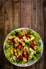 Salad with shrimps on wooden background