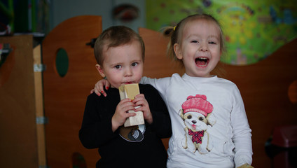 Funny little boy and girl drinking juice together in kindergarten