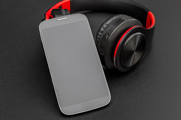 Bluetooth headphones with smartphone on black.