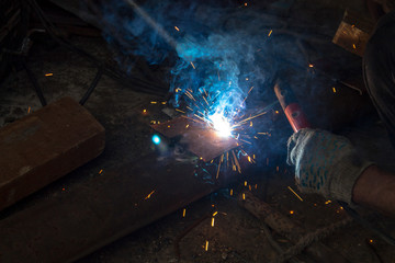 the work of the welding machine in the hands of the welder, welding sparks, industrial background