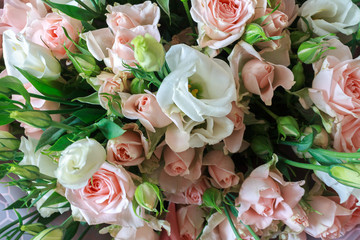 a bouquet of a variety of beautiful flowers like shrub roses and lisianthus eustoma on a wooden surface in nature