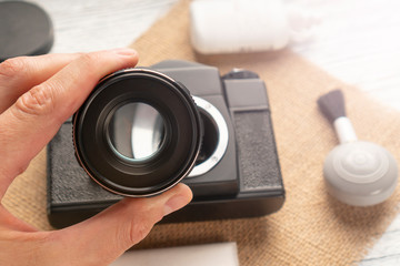 A hand holds the camera lens to check the cleanliness of the glass on a sack and wooden table