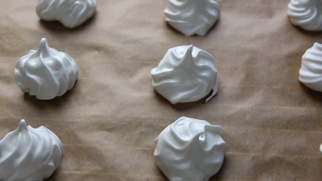 White meringue cookies on brown baking paper ready to bake, close up