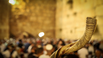 Shofar and in the background religious people pray at the Western Wall in the Holy City of Jerusalem in Israel - obrazy, fototapety, plakaty
