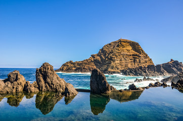 Fototapeta na wymiar Amazing natural swimming pools in the Atlantic ocean, Madeira Island, Portugal. Made up of volcanic rock, into which the sea flows naturally. Tourist attraction and summer vacation destination