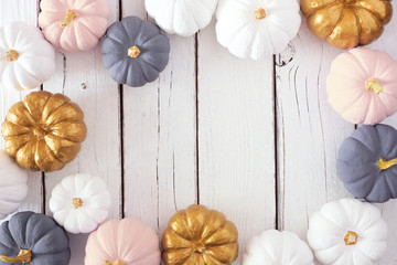 Autumn frame of dusty rose, white, gold and gray pumpkins on a white wood background. Modern muted pastel colors. Top view with copy space.