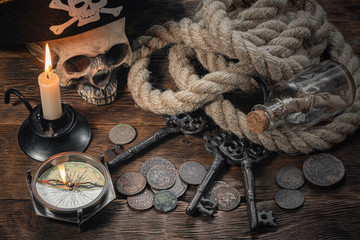 Pirate table background. Pirate hat, human skull, moorings, coins and compass on brown wooden table.