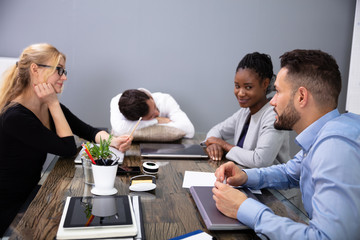 Man Sleeping On Office Desk During Meeting