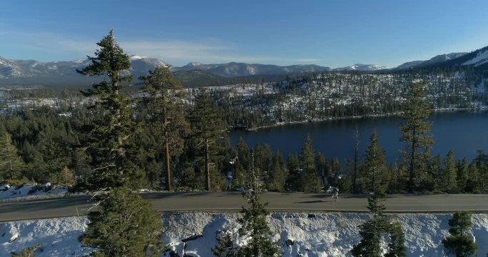 Aerial drone paralel shooting over running man by road at Lake Tahoe, USA, 4K