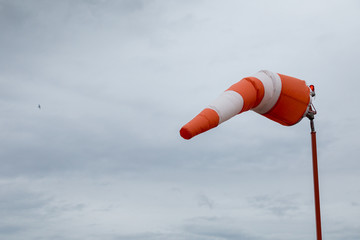 Red and white windsock with an aircraft in the distance.