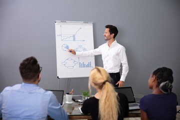 Obraz premium Young Businessman Giving Presentation To His Colleagues